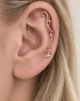 18k rose gold helix and lobe piercing jewelry with diamonds and pearls on a human ear