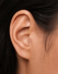 Delicate 18k gold cross earring in ear lobe, luxury handmade body jewelry for elegant style