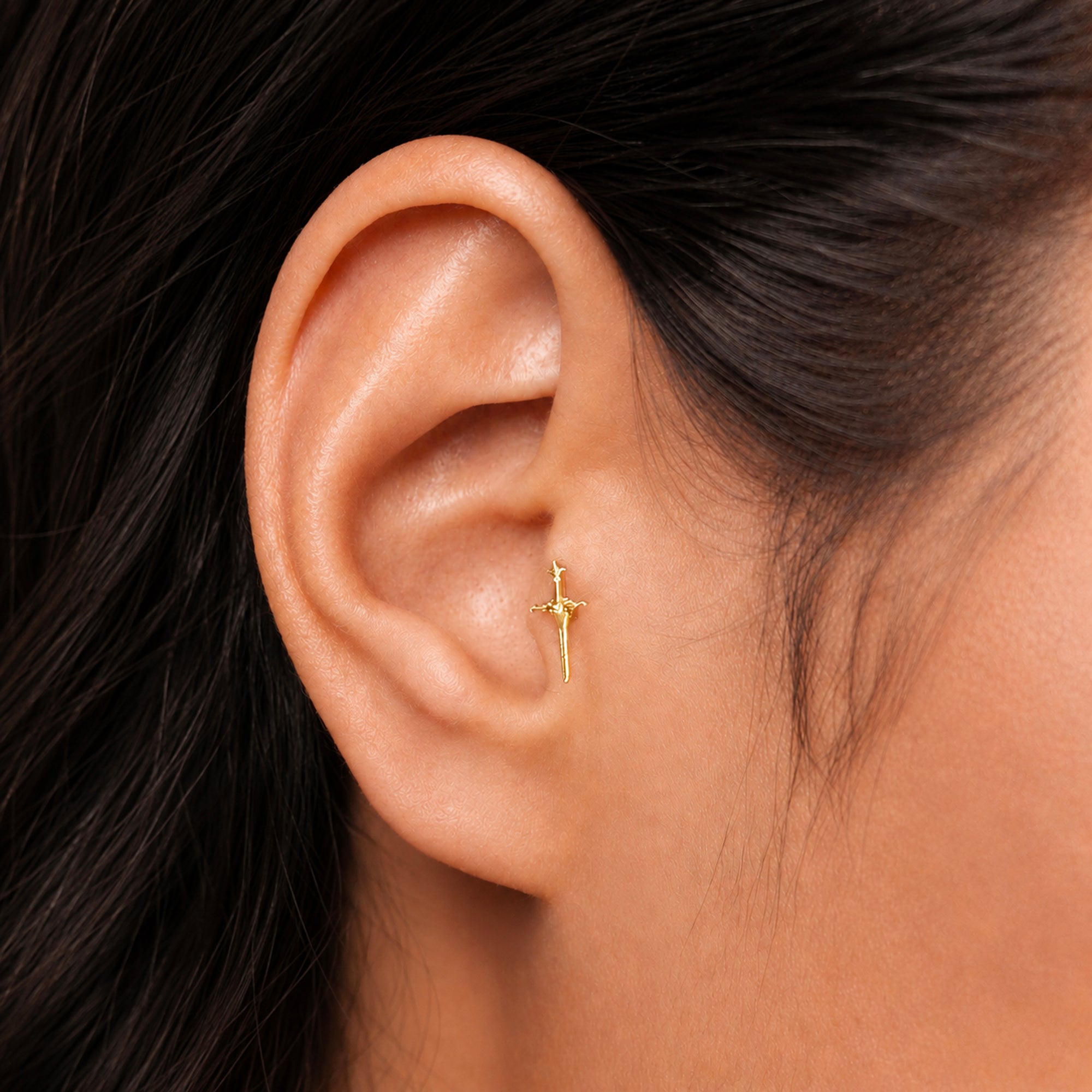 18k gold sword stud earring in ear, luxury piercing jewelry for elegant style