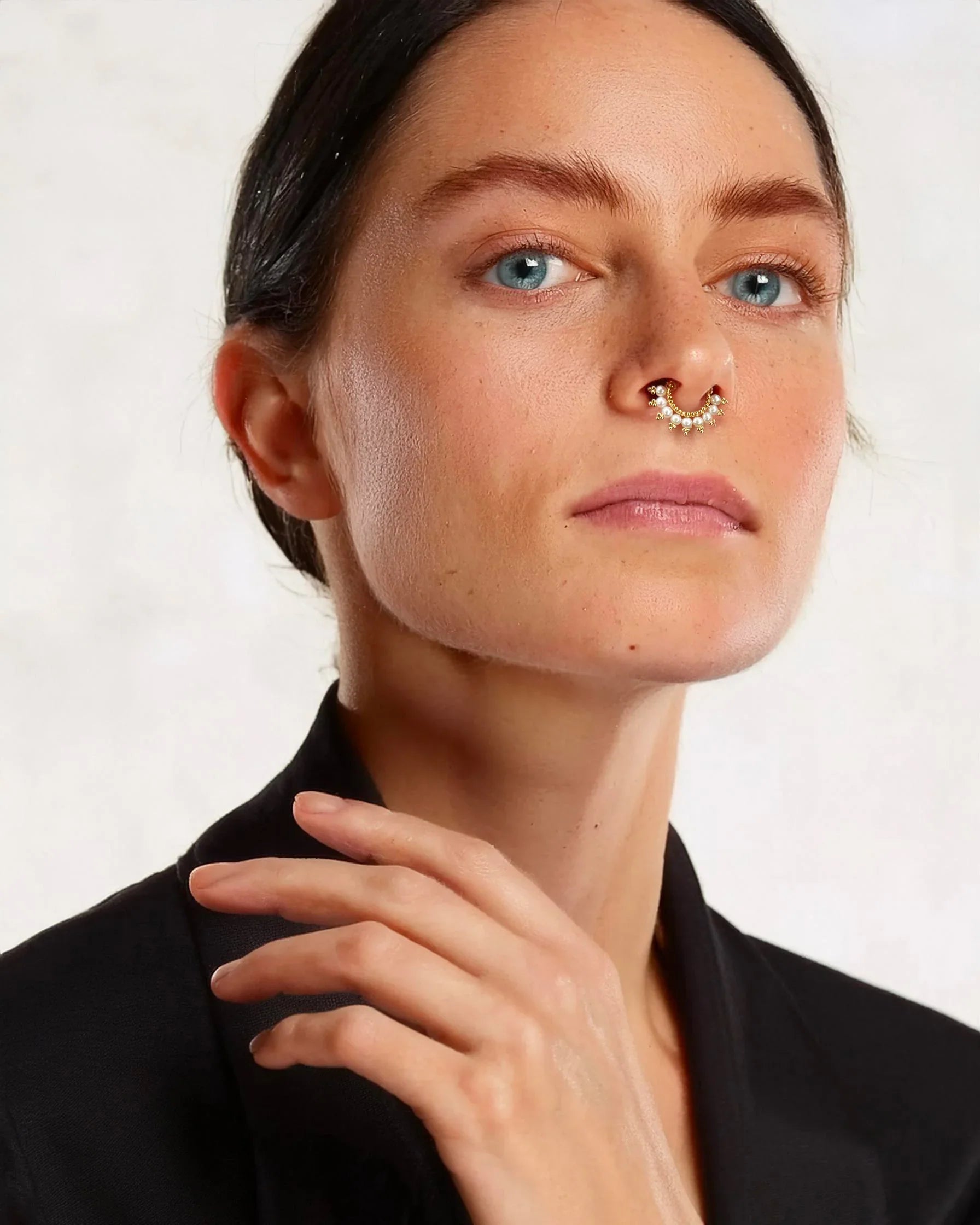 Woman wearing an 18k gold diamond septum piercing, luxury handmade nose jewelry